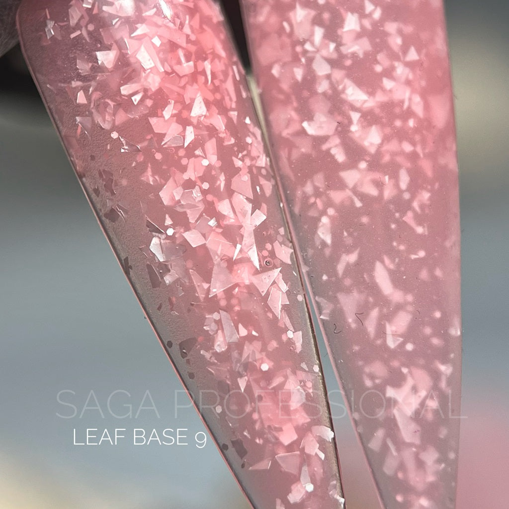 Close-up of pink glittery nail art design on a gray background with 'Saga Professional' branding.